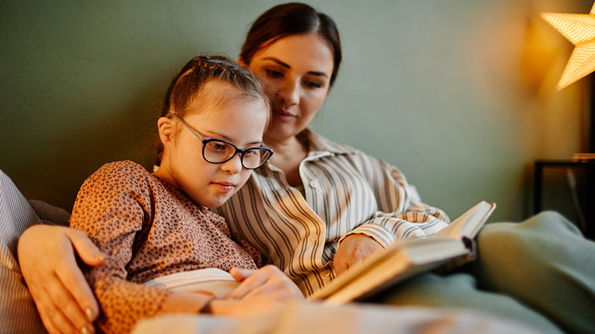 Mujer Leyendo Libro a Niña con Espectro Autista en Referencia a la Educación Sexual Infantil